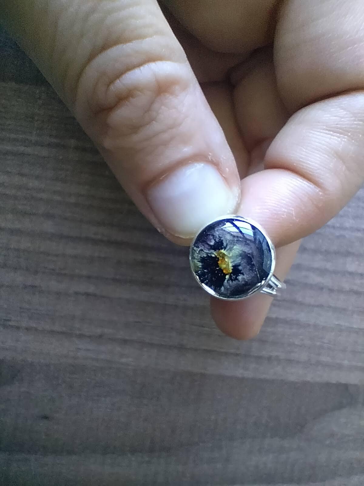 Bague réglable couleur argent avec inclusion d'une fleur séchée.